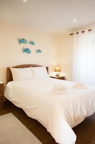 a bedroom with a large white bed with fish on the wall at CASAL RIQUEZO T2 - Serra da Pescaria - NAZARÉ in Nazaré