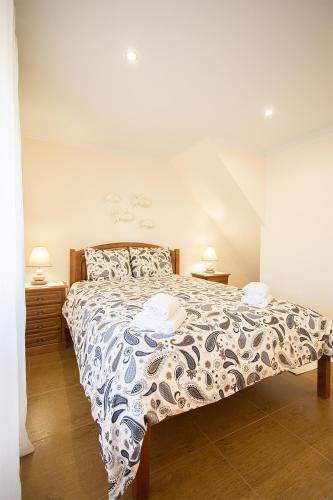 a bedroom with a bed with a blue and white comforter at CASAL RIQUEZO T2 - Serra da Pescaria - NAZARÉ in Nazaré