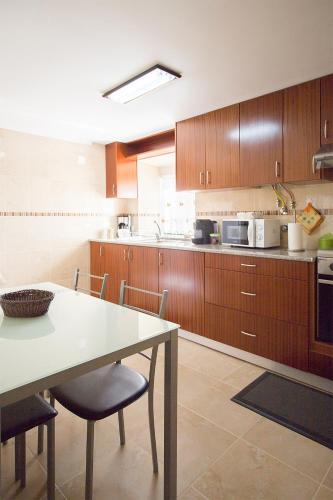 a kitchen with wooden cabinets and a table with chairs at CASAL RIQUEZO T2 - Serra da Pescaria - NAZARÉ in Nazaré
