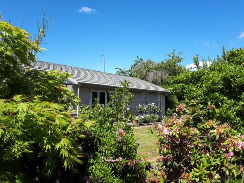 a house with trees and flowers in the yard at Edgewater Motel in Te Anau