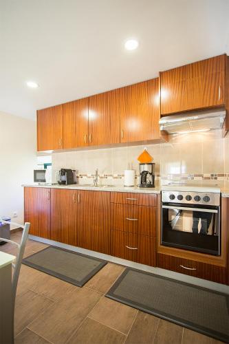 a kitchen with wooden cabinets and a stove at Casal Riquezo T2-1.o- Serra da Pescaria - Nazare in Nazaré