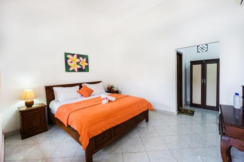 1 dormitorio con 1 cama con manta naranja en Arya Inn Enny Salon and Spa, en Nusa Lembongan