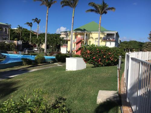 une maison avec une cour avec piscine et palmiers dans l'établissement Studio Anse des Rochers, à Saint-François