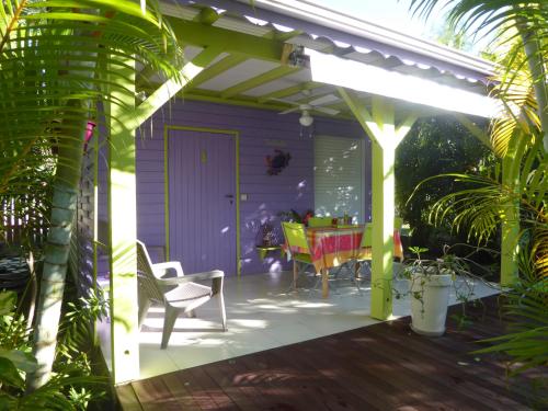 a purple house with a patio with a table at Coco Bungalows in Sainte-Rose