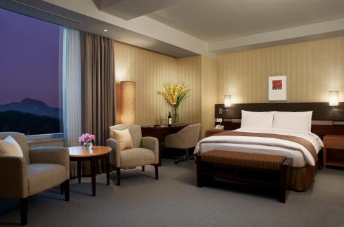 a hotel room with a bed and a desk and chairs at Grand Plaza Cheongju Hotel in Cheongju