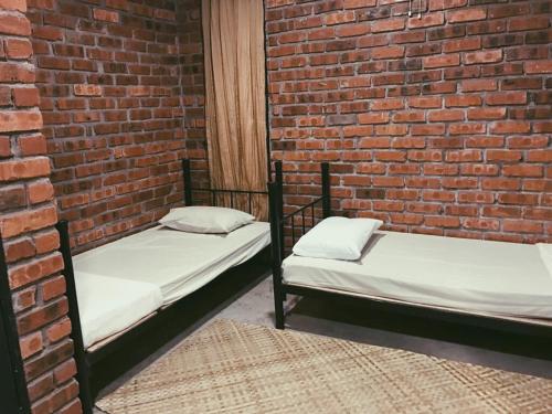 two beds sitting against a brick wall at Rareheart Guesthouse in Kuala Terengganu
