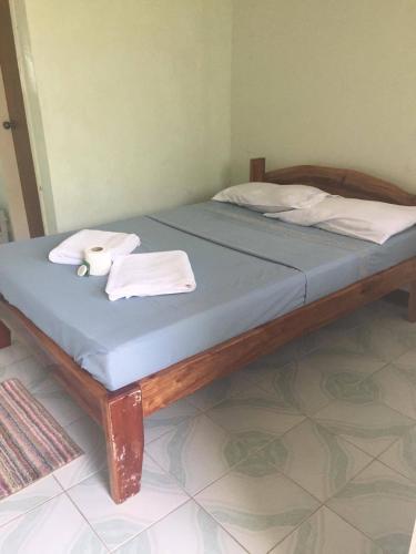 a bed with a wooden frame with towels on it at Cliff Side Beach Resort and Cottages in Lomangcapan