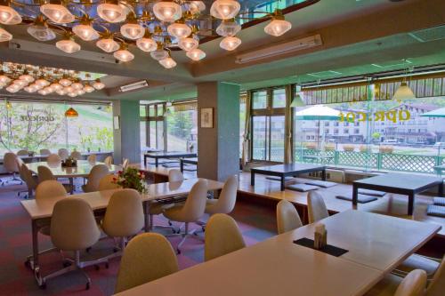 a dining room with tables and chairs and windows at Biwaike Hotel in Yamanouchi
