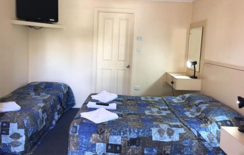 a hotel room with two beds and a tv at Forster Beach Motel in Forster