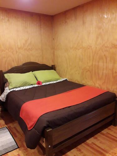 a bedroom with a bed with a wooden wall at La casa del Kori in Hanga Roa