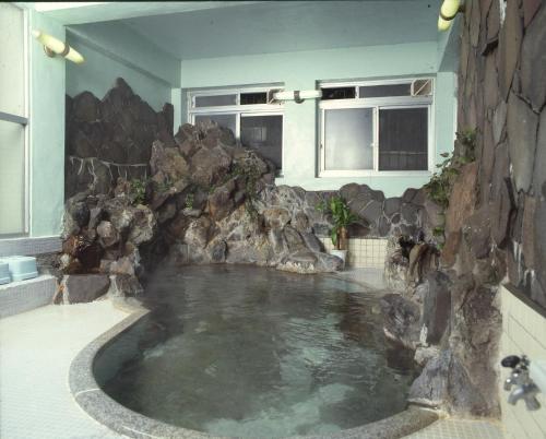 una gran piscina de agua en una habitación con rocas en Motoyu Arimaya, en Aizuwakamatsu