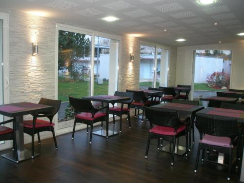 a dining room with tables and chairs and windows at Charme Hôtel, Montbéliard Sud in Montbéliard