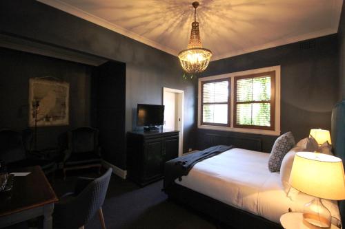 a bedroom with a bed, a lamp, and a window at Berida Hotel in Bowral