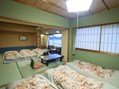 Cette chambre comprend 4 lits, une table et des fenêtres. dans l'établissement Shimoda Itoen Hotel Hanamisaki, à Shimoda