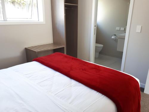 a red blanket laying on top of a bed in a bedroom at Edgewater Motel in Te Anau
