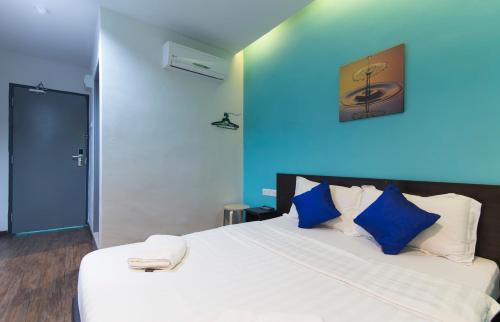 a bedroom with a large white bed with blue walls at Clover Hotel Ipoh in Ipoh