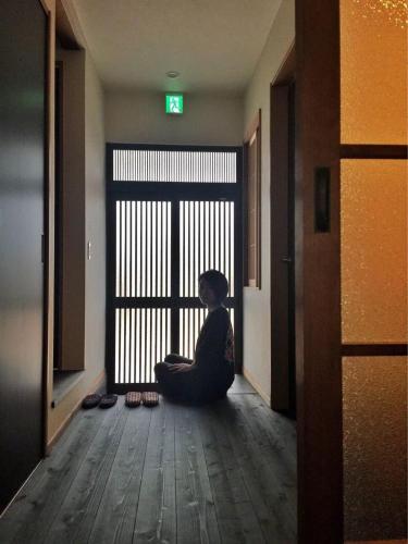 a woman sitting on the floor in front of a door at Yuenshe Sanjusangendo Villa in Kyoto