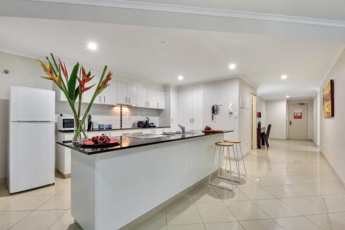 a kitchen with a counter and a white refrigerator at Argus Apartments Darwin in Darwin