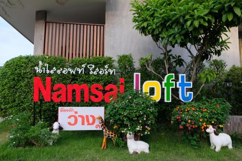 a sign in front of a house with animals in the grass at Nam Sai Loft Resort in Chao Lao Beach