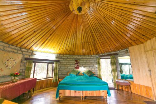 a bedroom with a bed and a wooden ceiling at Khali Estate in Binsar