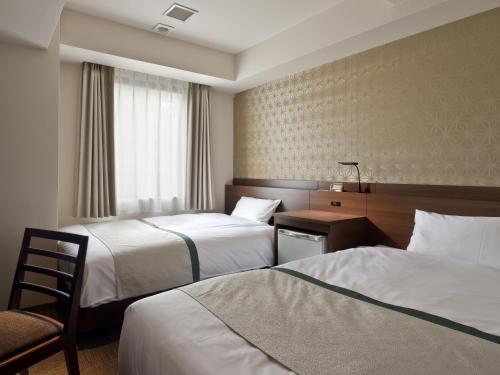 Habitación de hotel con 2 camas y mesa con silla en Tosei Hotel Cocone Kanda, en Tokio