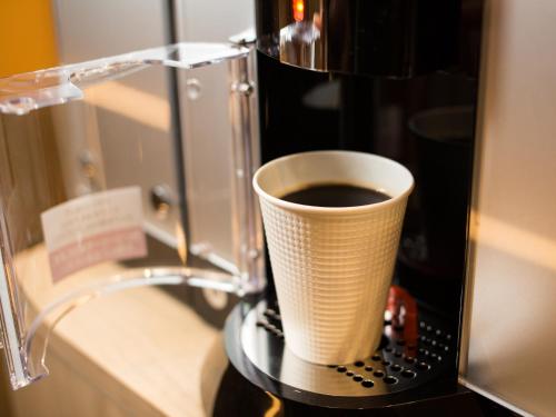 a cup of coffee sitting on top of a coffee machine at Tosei Hotel Cocone Kanda in Tokyo