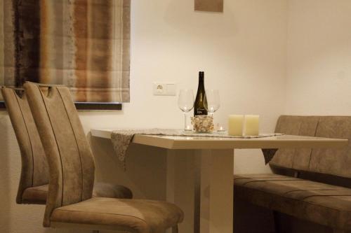 a table with a bottle of wine and two chairs at Apartments Fuchs in Grundlsee