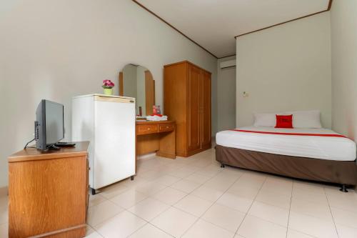 Un dormitorio con una cama y un televisor en una habitación. en Reddoorz Plus @ Karet Pedurenan 3, en Yakarta