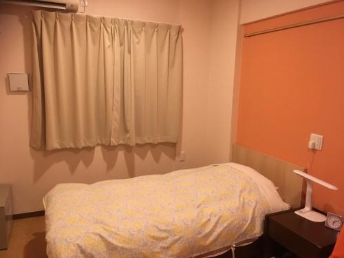 a bedroom with a white bed and a window at Hotel Asahi Grandeur Fuchu in Fuchu