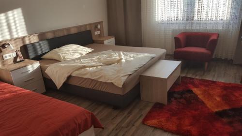 um quarto com uma cama e uma cadeira vermelha em Ferienhaus Karall em Klingenbach