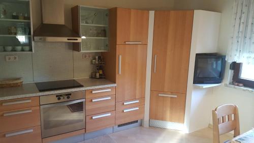 a kitchen with wooden cabinets and a tv on the wall at Ferienhaus Karall in Klingenbach