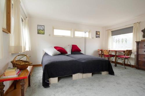 a bedroom with a bed with red pillows and a table at Studio on a houseboat, near city centre! in Amsterdam