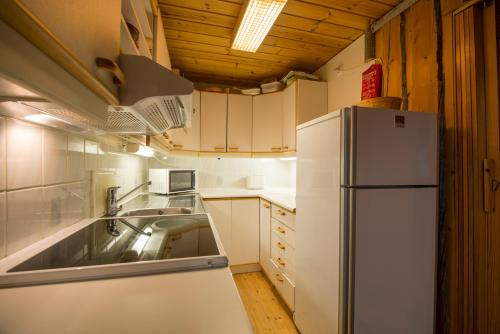 a kitchen with a white refrigerator and a sink at Hillankukka in Äkäslompolo