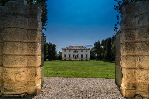 a large white house in a field behind a gate at La Barchessa di Villa Pisani in Lonigo