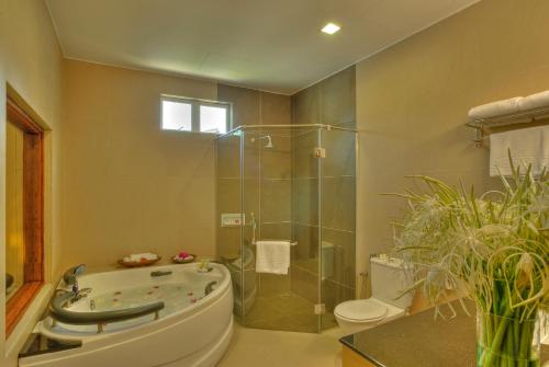 a bathroom with a tub and a toilet and a shower at Frangipani Langkawi Resort in Pantai Cenang