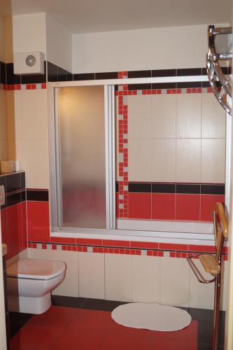a red and white bathroom with a toilet and a window at Apartments Klinovec in Loučná pod Klínovcem