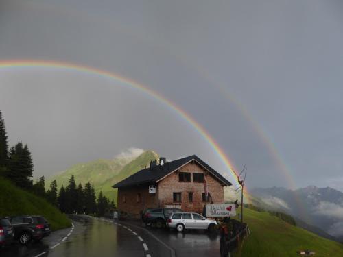 a rainbow over a building with cars parked on a road at Hotel Jägerstüble in Damuls