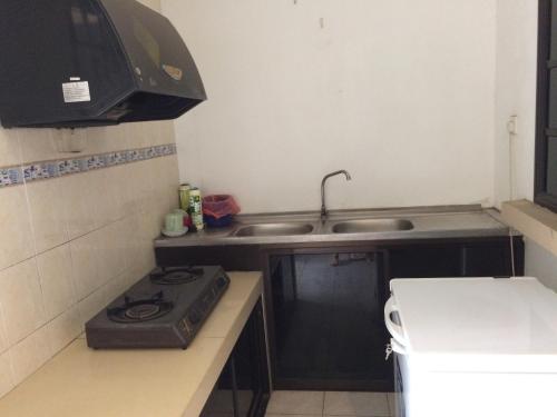 a small kitchen with a stove and a sink at Golden Swan Sibu Homestay in Sibu