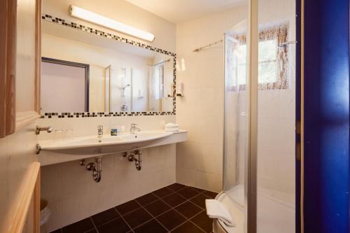 a bathroom with a sink and a shower at Hotel Enzian by Alpeffect Hotels in Zauchensee