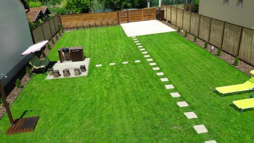 a backyard with a lawn with chairs and tables at Velence Korzó Pihenőház in Kápolnásnyék