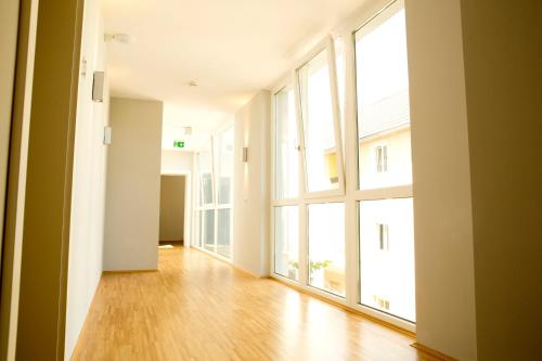 an empty room with large windows and a wooden floor at Pfeiler's Bürgerstüberl - Hotel in Feldbach