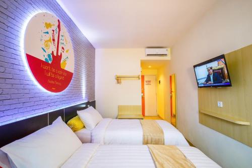 a hotel room with two beds and a tv at Front One Inn Muntilan in Muntilan
