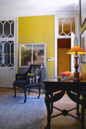 a room with a table and a chair and a yellow wall at La Divine Comédie-Suites Deluxe in Avignon