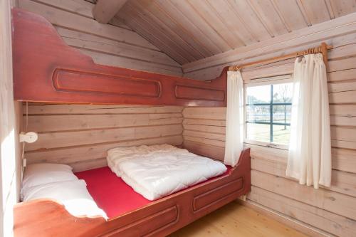 a bed in a log cabin with a window at Hamre Familiecamping in Kristiansand