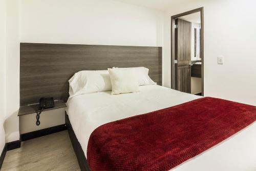 a bedroom with a large bed with a red blanket at Hotel Express 53 in Bogotá