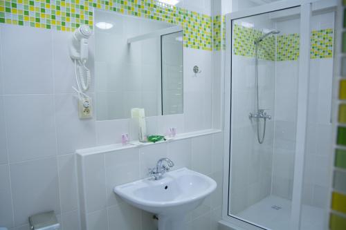 a white bathroom with a shower and a sink at UYUTNYY DOM in Taraz