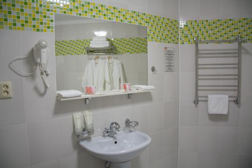 a white bathroom with a sink and a mirror at UYUTNYY DOM in Taraz