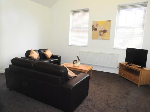 a living room with a black couch and a television at Parks Nest 3 in Hull