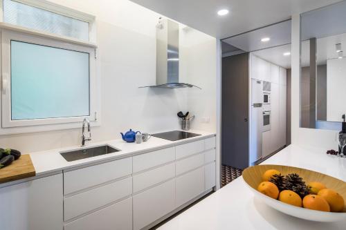a kitchen with white cabinets and a bowl of fruit at Habitat Apartments Garden View in Barcelona
