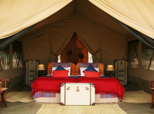 a bed with red and blue pillows in a tent at Olengoti Eco Safari Camp in Talek